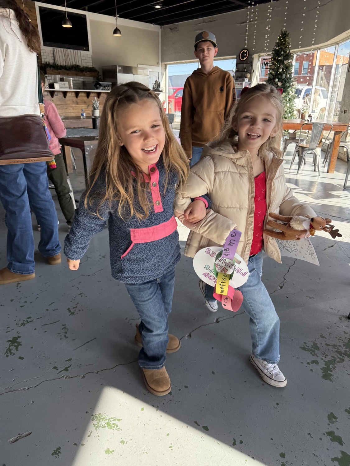 Two girls smiling and holding the crafts they made