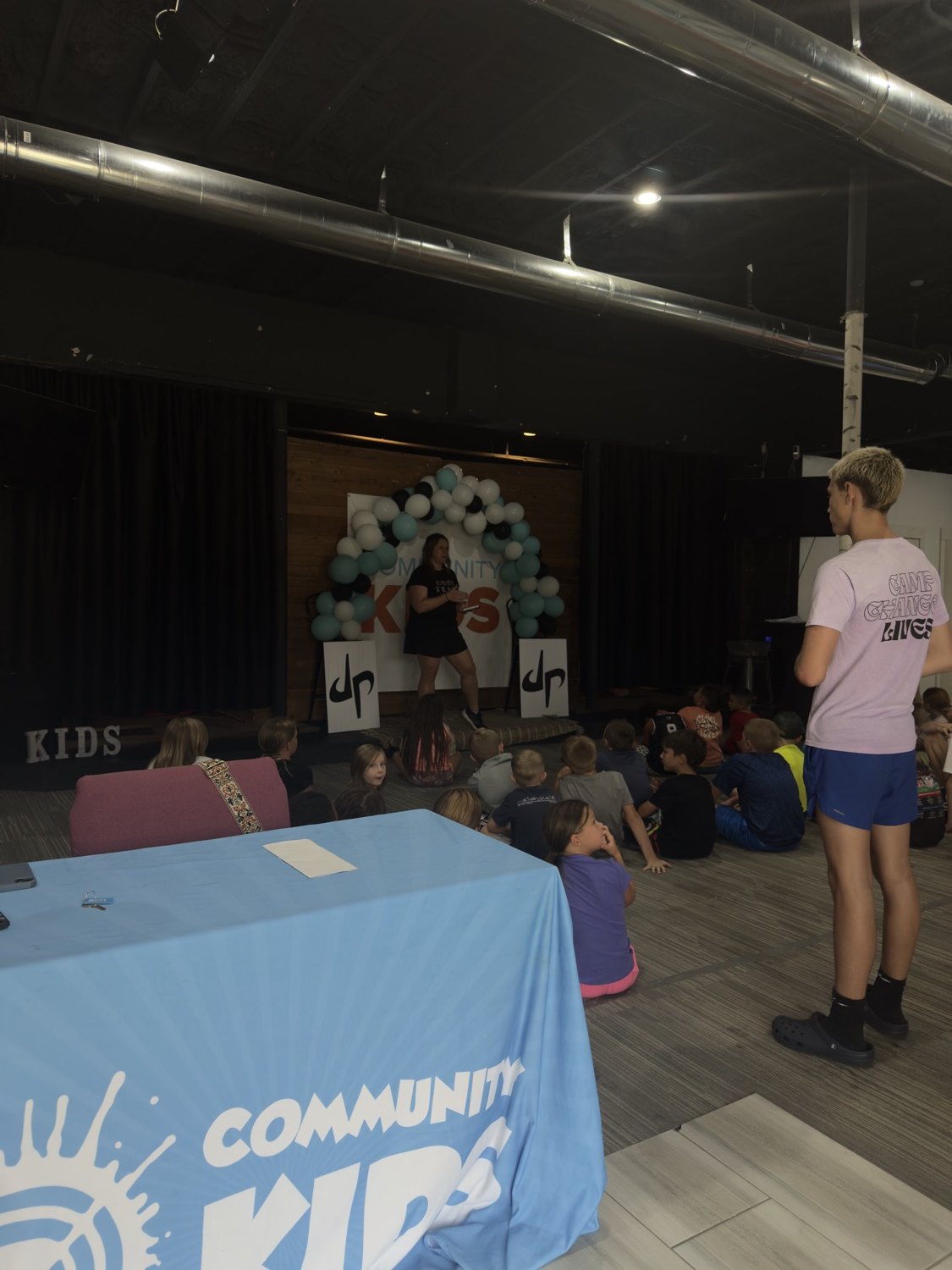 A leader teaching kids gathered on the floor