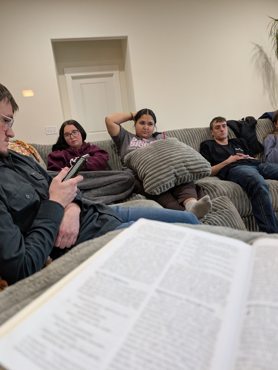 Young adults on the couch with an open Bible
