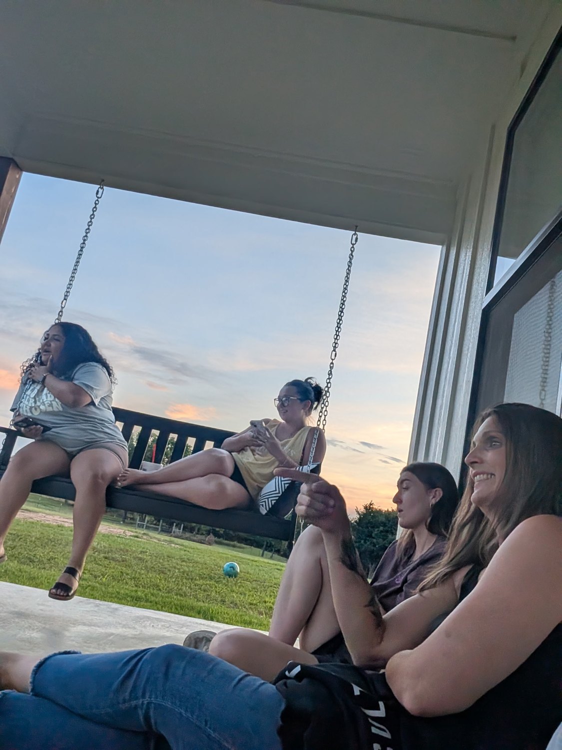 Young adults on a porch swing at sunset