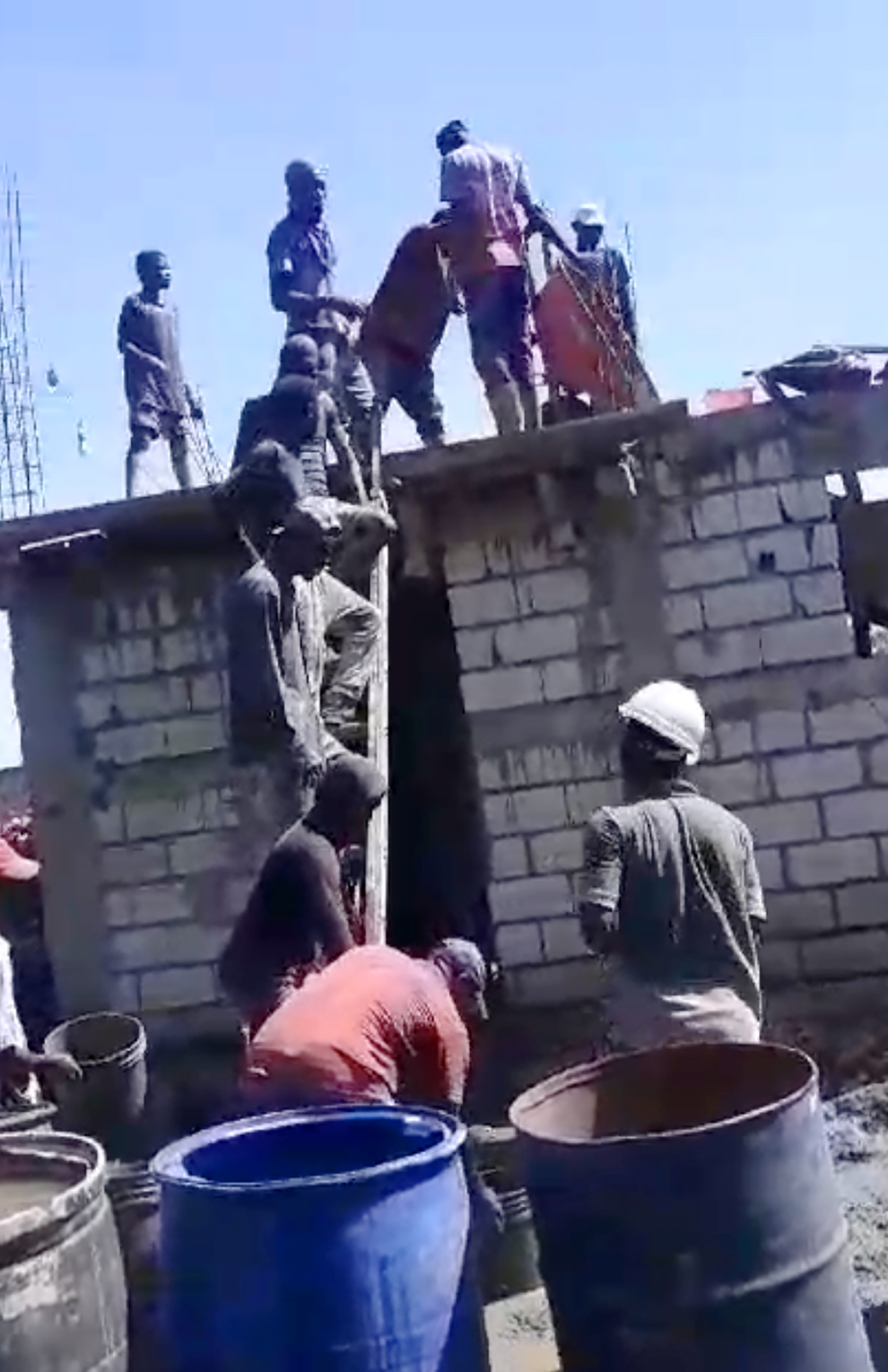 Haitian men lifting concrete up a ladder as they build a church building in Haiti.
