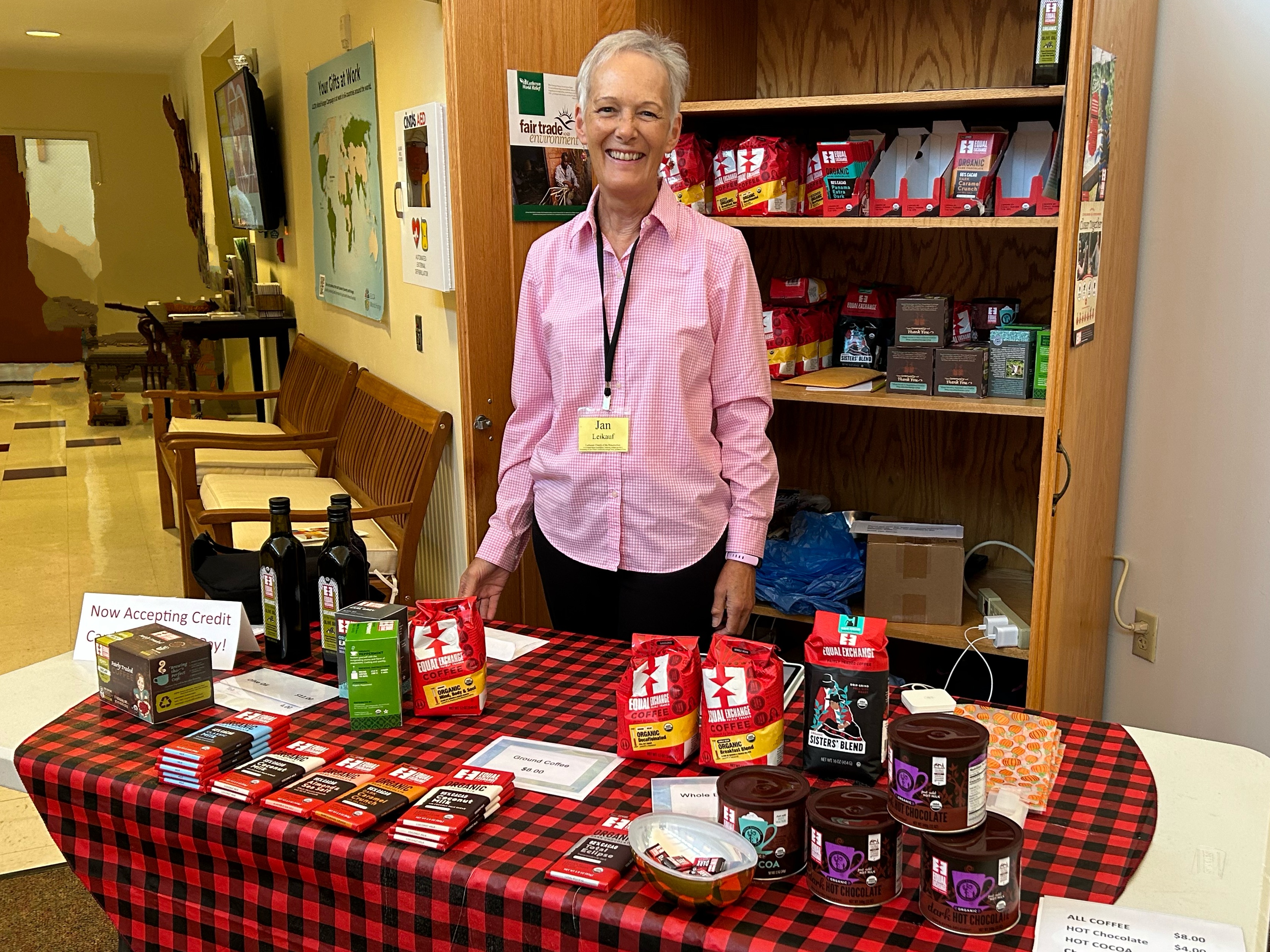 Woman stands at table with fair trade items for sale